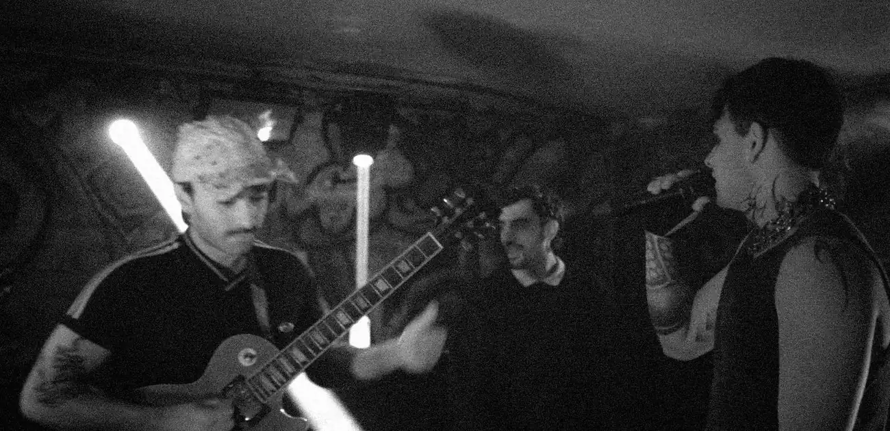 Guitarrista con gorra, otro músico y Cap Kuo al micrófono