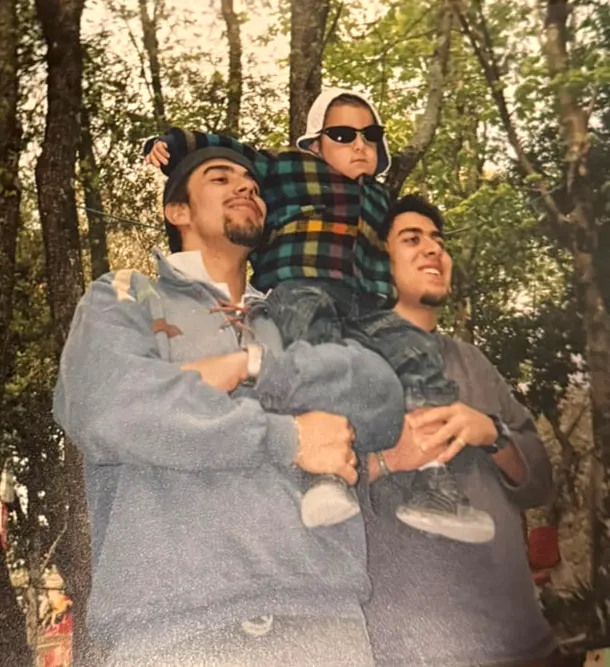 Cap Kuo de chico, con anteojos oscuros y capucha, en andas de dos familiares